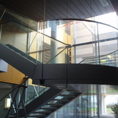 Escalier acier avec garde-corps vitré cintré dans un hall d'hôpital